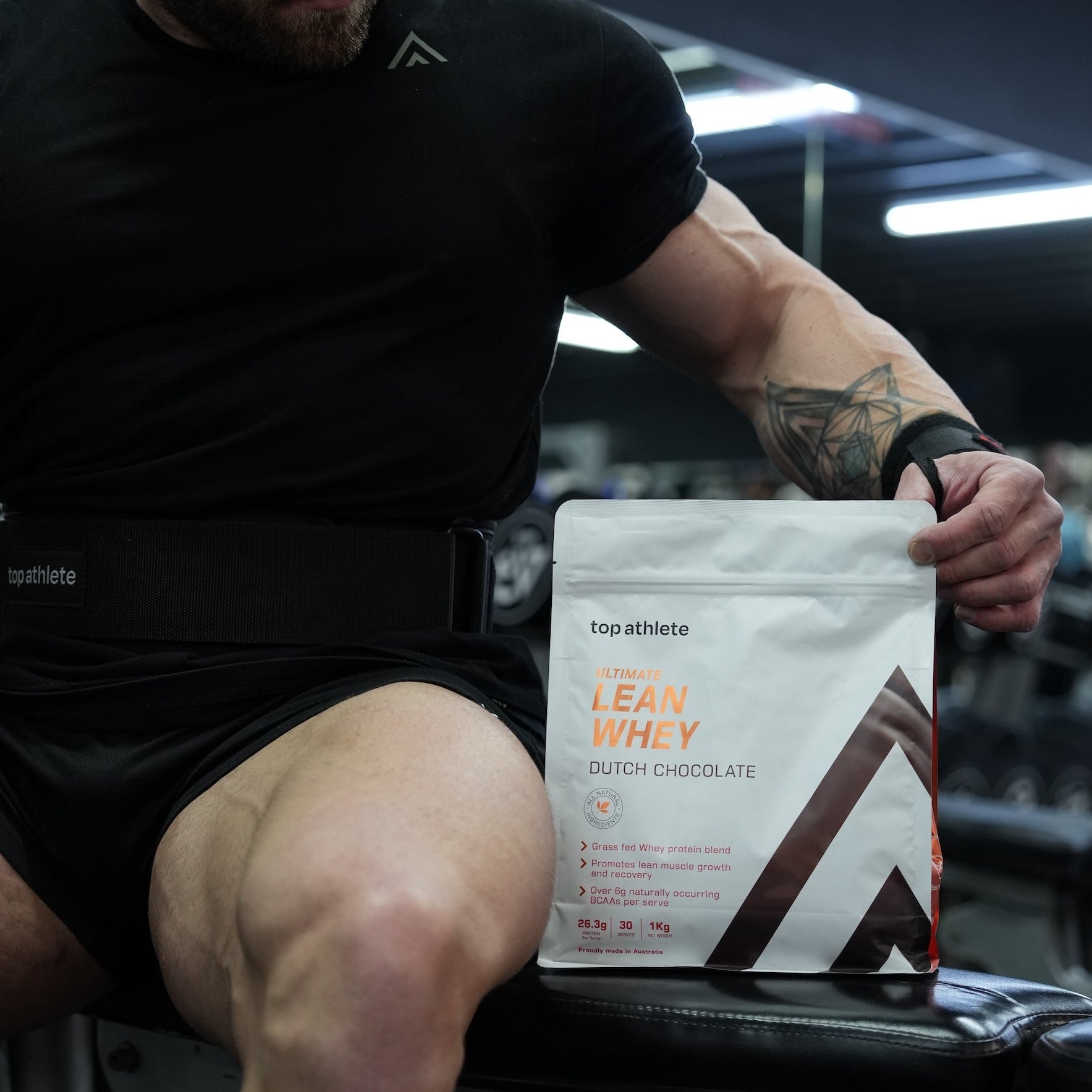Athlete sitting on a gym bench holding a protein powder package.